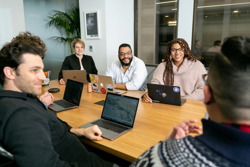 Group of six colleagues at LMG Inc. sitting around a table and talking