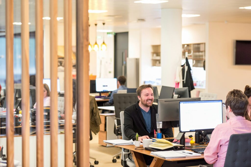 Employees working and talking at desks in an open office with computers